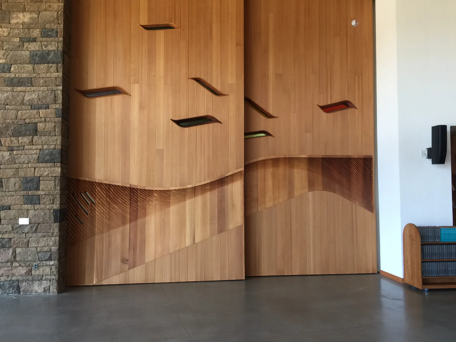 Custom sculpted wood panels and doors with inlaid glass beside a stone wall