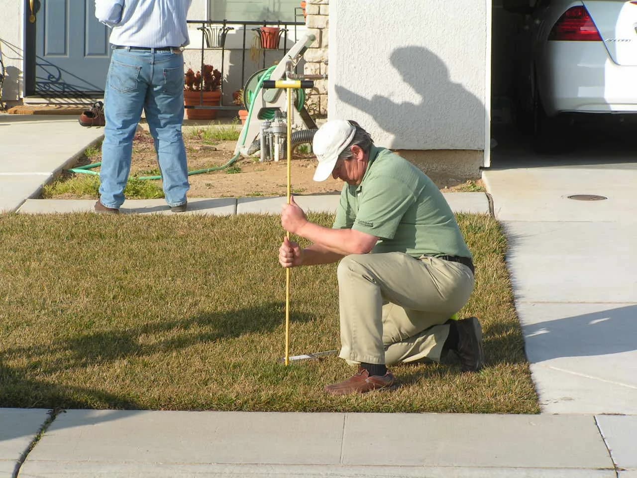 Lyle Coe investigating yard drainage conditions at a residential site