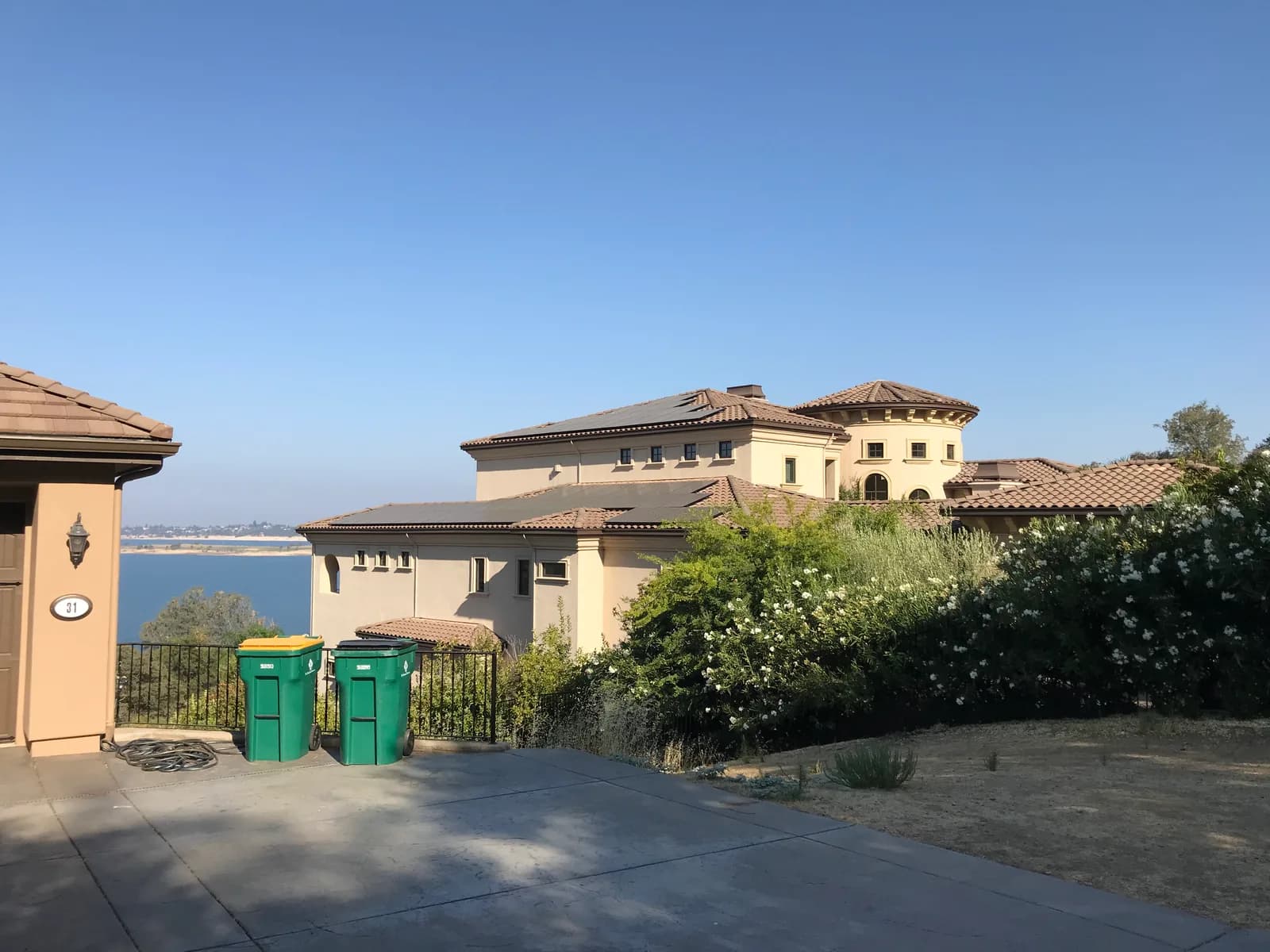 Multi-wing custom residence with tile roofs and rooftop solar panels overlooking a lake