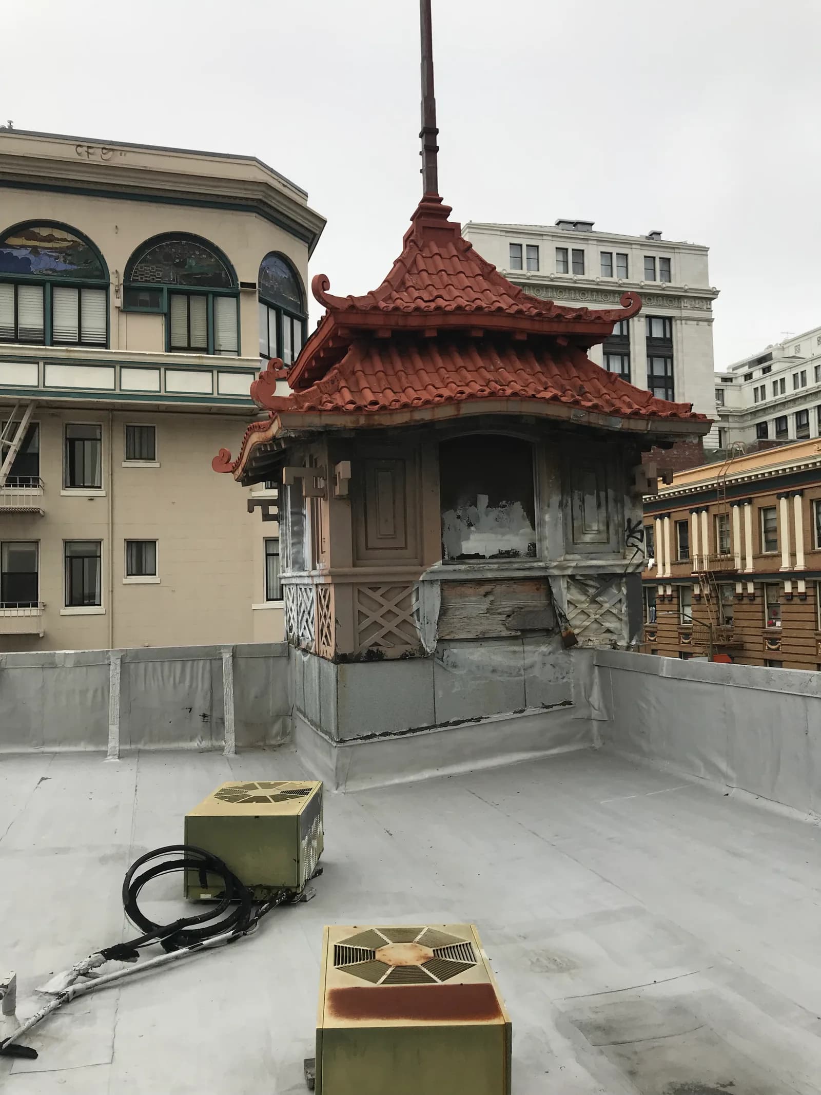 Rooftop HVAC condensing units beside a deteriorated pagoda-style cupola on a San Francisco building